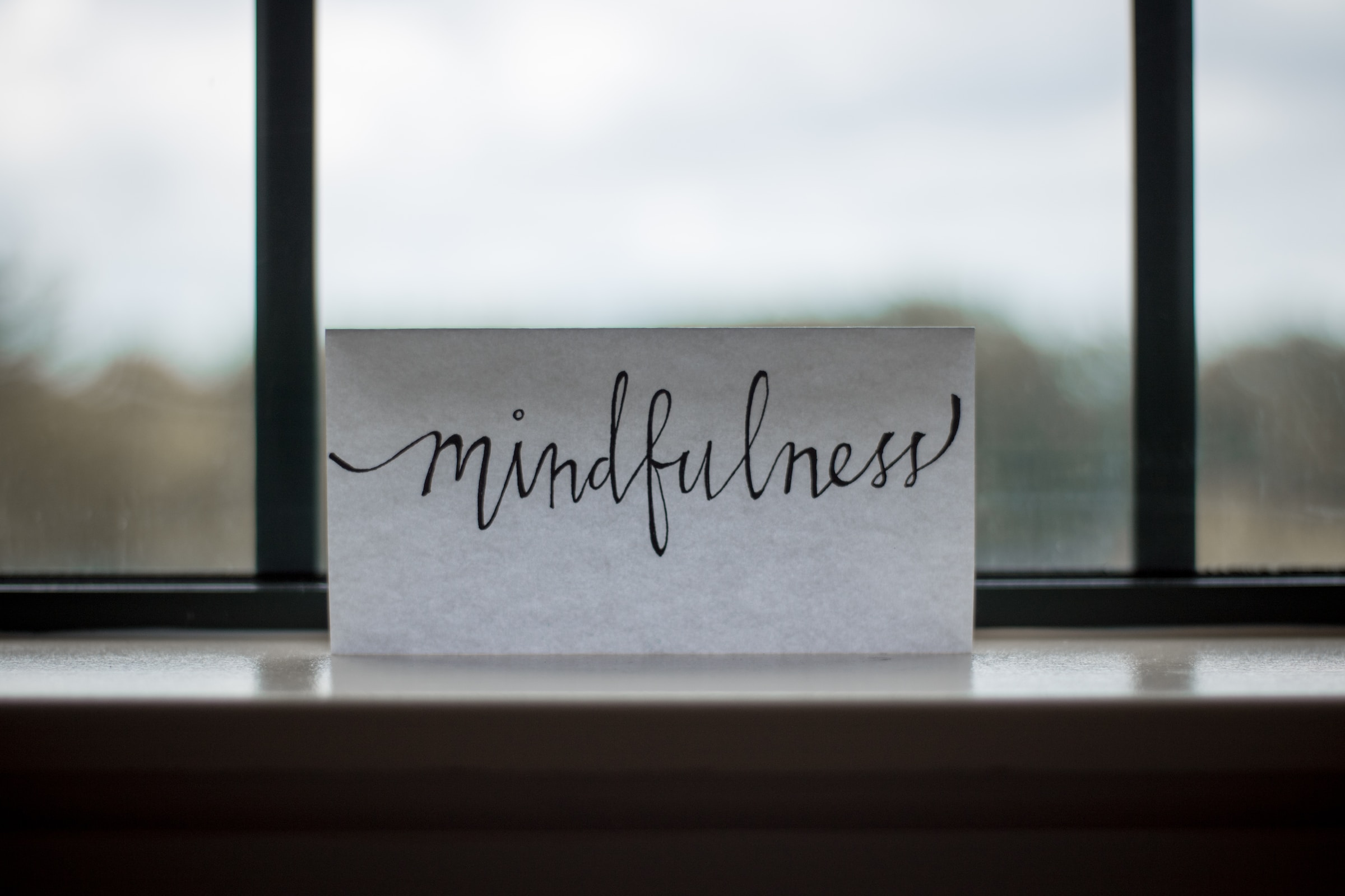 sign in window sill with the word 'mindfulness' written in cursive